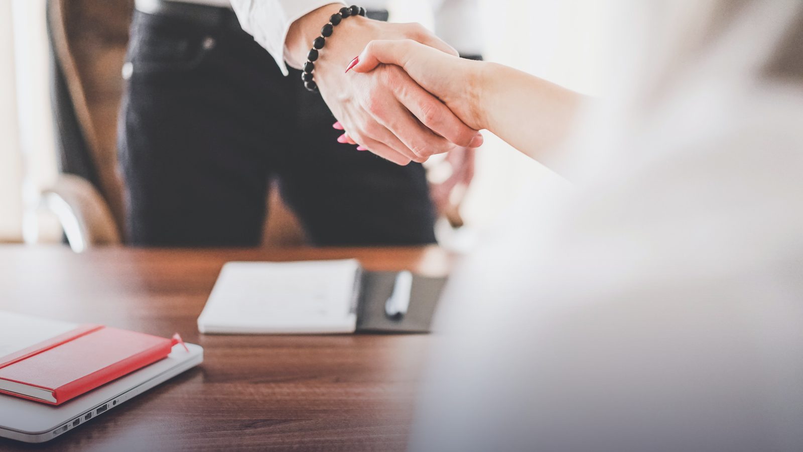 Two people shaking hands across a desk